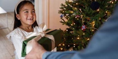 Jente foran juletre, som får julegave 