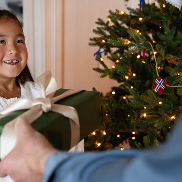 Jente foran juletre, som får julegave 