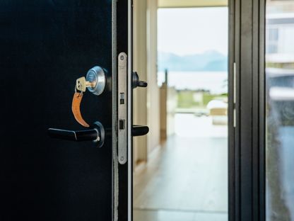 Svart ytterdør som står på gløtt med nøkkelen i. 