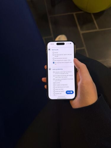 Hånd som holder mobiltelefon som viser skatteetaten sine nettsider. 