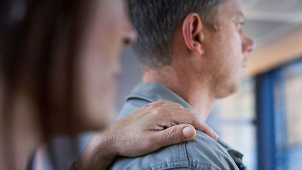 Nærbilde av kvinne som holder en hånd på skulderen til en mann, begge ser ut et vindu