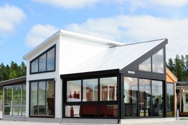Moderne hus i hvitt og sort med skrå tak og mye vindu. 