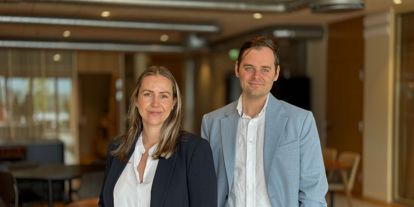 Mann og kvinne i dressjakke og hvit skjorte. Moderne kontorlokaler i bakgrunn 
