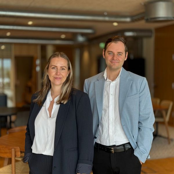 Mann og kvinne i dressjakke og hvit skjorte. Moderne kontorlokaler i bakgrunn 
