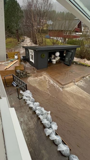 Utsikt som viser en hagestue som er oversvømmet med vann fra nærliggende elv. 