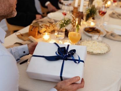 Juledekket bord med en julegave pakket i hvitt papir og blått bånd. 