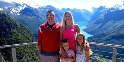 En familie med to voksne og to barn står på en utsiktsplass.