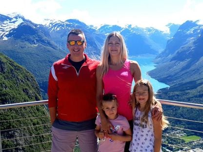 En familie med to voksne og to barn står på en utsiktsplass.