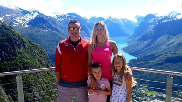 En familie med to voksne og to barn står på en utsiktsplass.