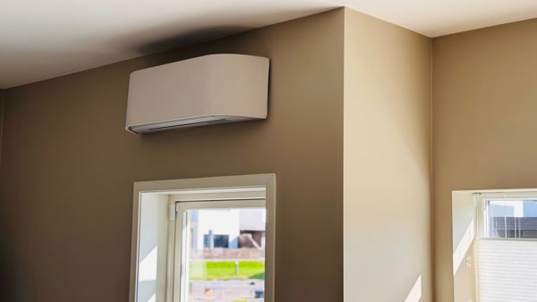 Bilde av en varmepumpe i et hus med beige vegger og solskinn.