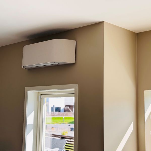Bilde av en varmepumpe i et hus med beige vegger og solskinn.