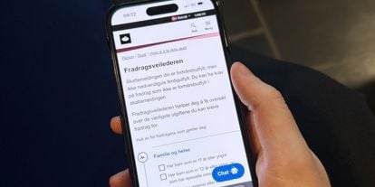 En hånd som holder en mobiltelefon som viser Skatteetaten sine nettsider. 