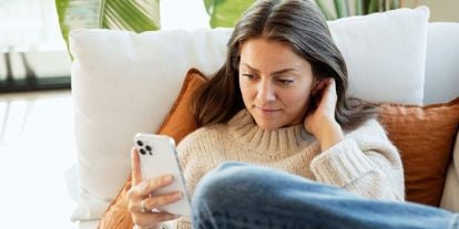 Dame i sofa med mobilen. Rolige omgivelser. 