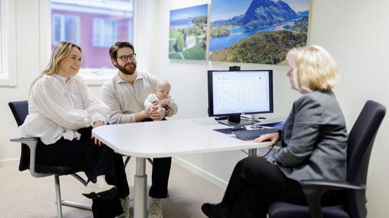Ungt par med baby på hånden i møte med bankrådgiver, i bankens lokaler 