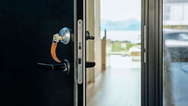 Åpen ytterdør med nøkkel i. Innsikt til moderne hus med utsikt mot fjord og fjell. 