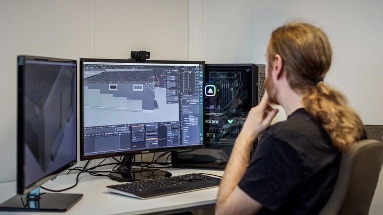 Ansatt sitter foran flere dataskjermer og arbeider med digitale modeller og grafikk på kontor hos Spesialistbedriften.
