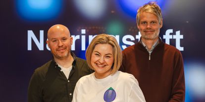 To menn og en dame står sammen og ser inn i kamera. På skjerm bak kan man skimte at det står Næringsteft. 