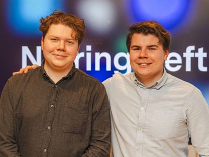 To menn med skjorte står sammen og smiler i kamera. Mann til høyre holder hånden på skulderen til den andre. I bakgrunn en skjerm der man skimter at det står Næringsteft.