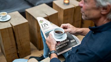 Mann som drikker kaffe og leser avis