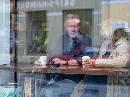 Mann og dame som sitter ved vindusplass på cafe