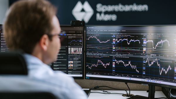 Megler som følger med på kursutvikling på to skjermer. Sparebanken Møre logo på vegg i bakgrunnen. 