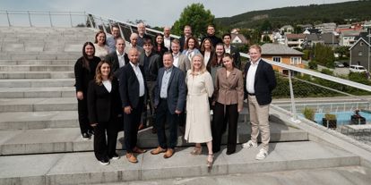 Bildet viser alle ansatte i Møremegling i en solfylt trapp, som smiler. 