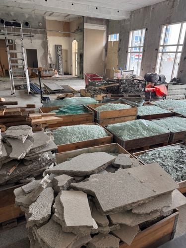 Kasser med knust stein og glass inne i et rehabiliteringsprosjekt. 