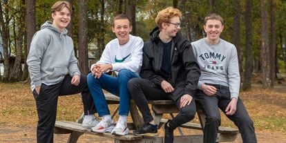 Fire kompiser på 15 år sitter på en benk.