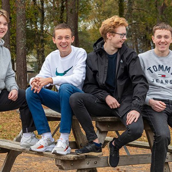 Fire kompiser på 15 år sitter på en benk.