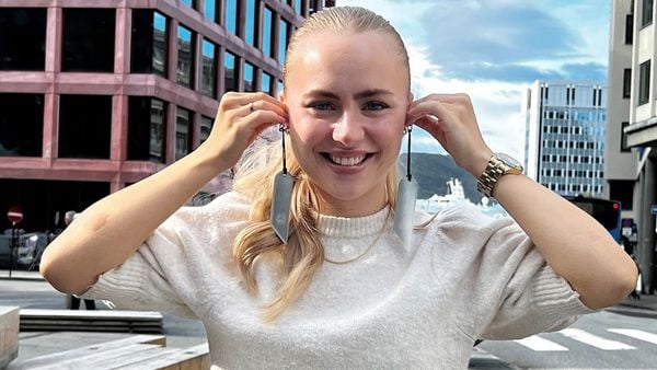 Ung dame som holder to refleks opp til ørene, som om de var øredobber.