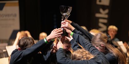Ungdommer i mørke gensere står sammen og løfter en pokal