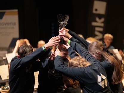 Ungdommer i mørke gensere står sammen og løfter en pokal