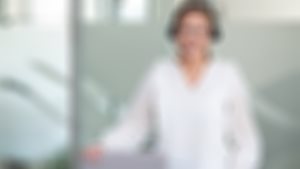 Rådgiver i Sparebanken Møre med headset på hodet smiler til deg.