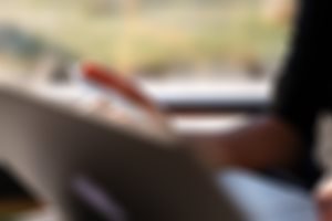 En person holder et mastercard i hånden og en PC i fanget.